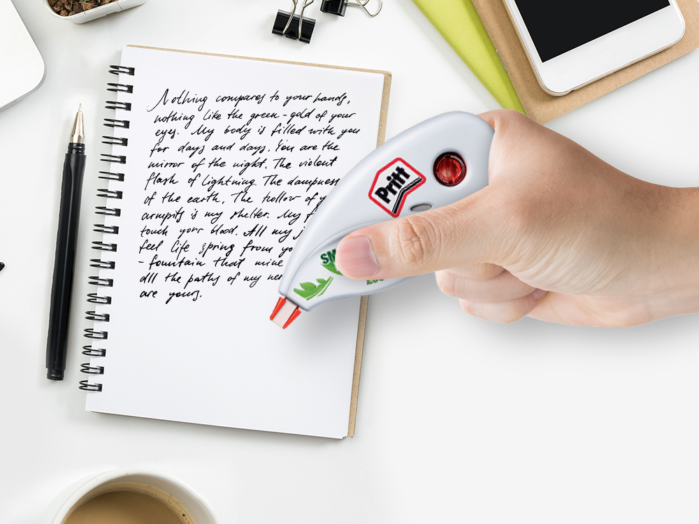 Pritt Ecomfort Roller Corrector em uma mão na frente de um bloco de notas