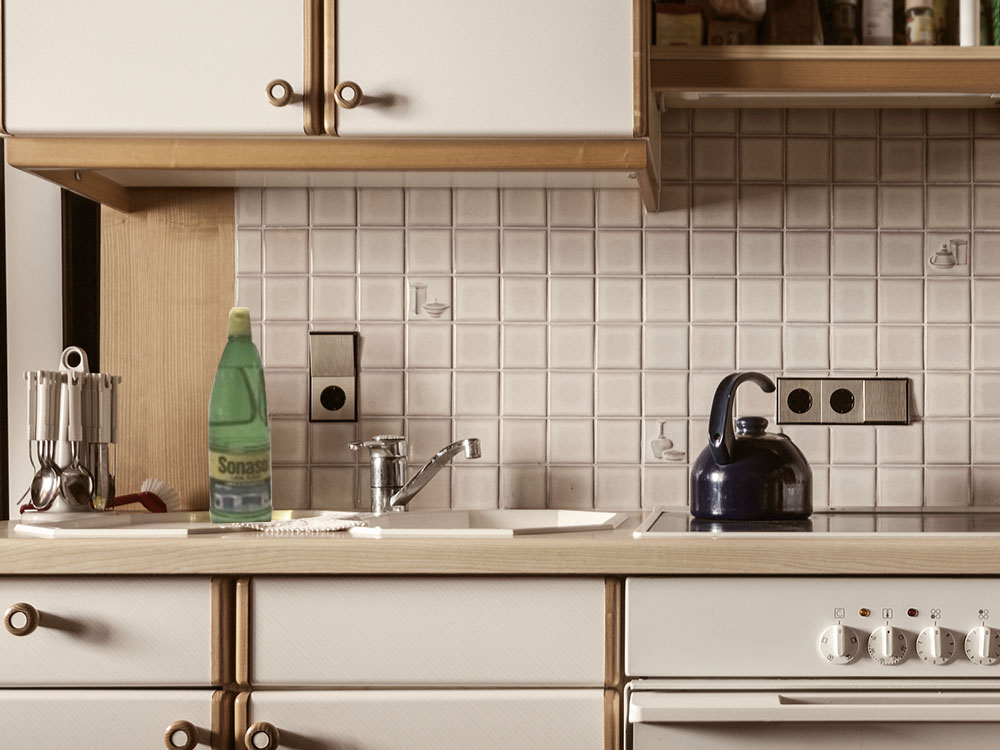 Seção de uma cozinha branca com bordas marrons no design dos anos 70.