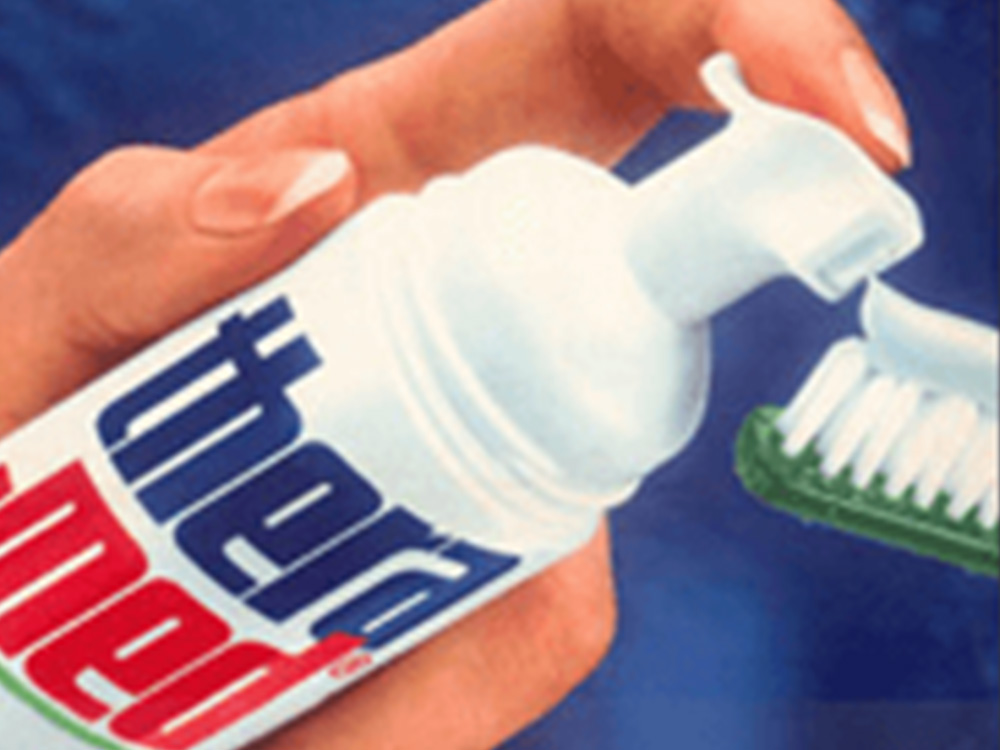 Close de um tubo Theramed e uma escova de dentes verde com pasta de dente