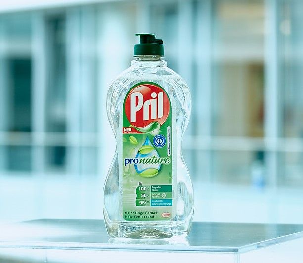 A bottle of the dishwashing product Pril Pro Nature standing on a transparent table.