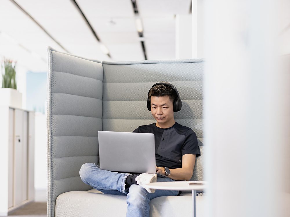 Um funcionário da Henkel com fones de ouvido trabalha concentrado em seu laptop. 