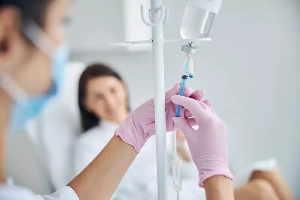 Profissional de saúde a segurar uma bolsa de soro intravenoso em ambiente hospitalar.