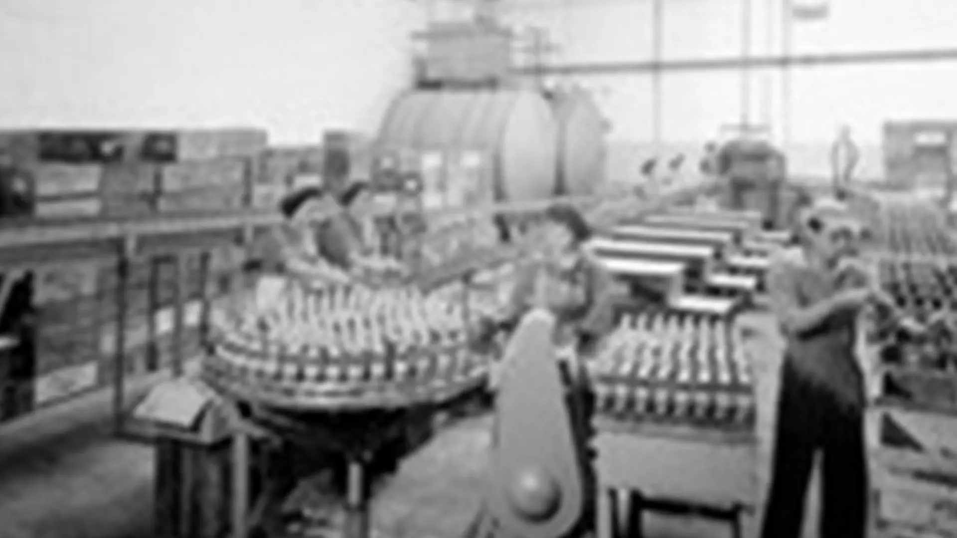 Linha de produção da Sociedade Nacional de Sabões em Portugal, adquirida pela Henkel em 1991, com garrafas alinhadas e trabalhadores na fábrica.