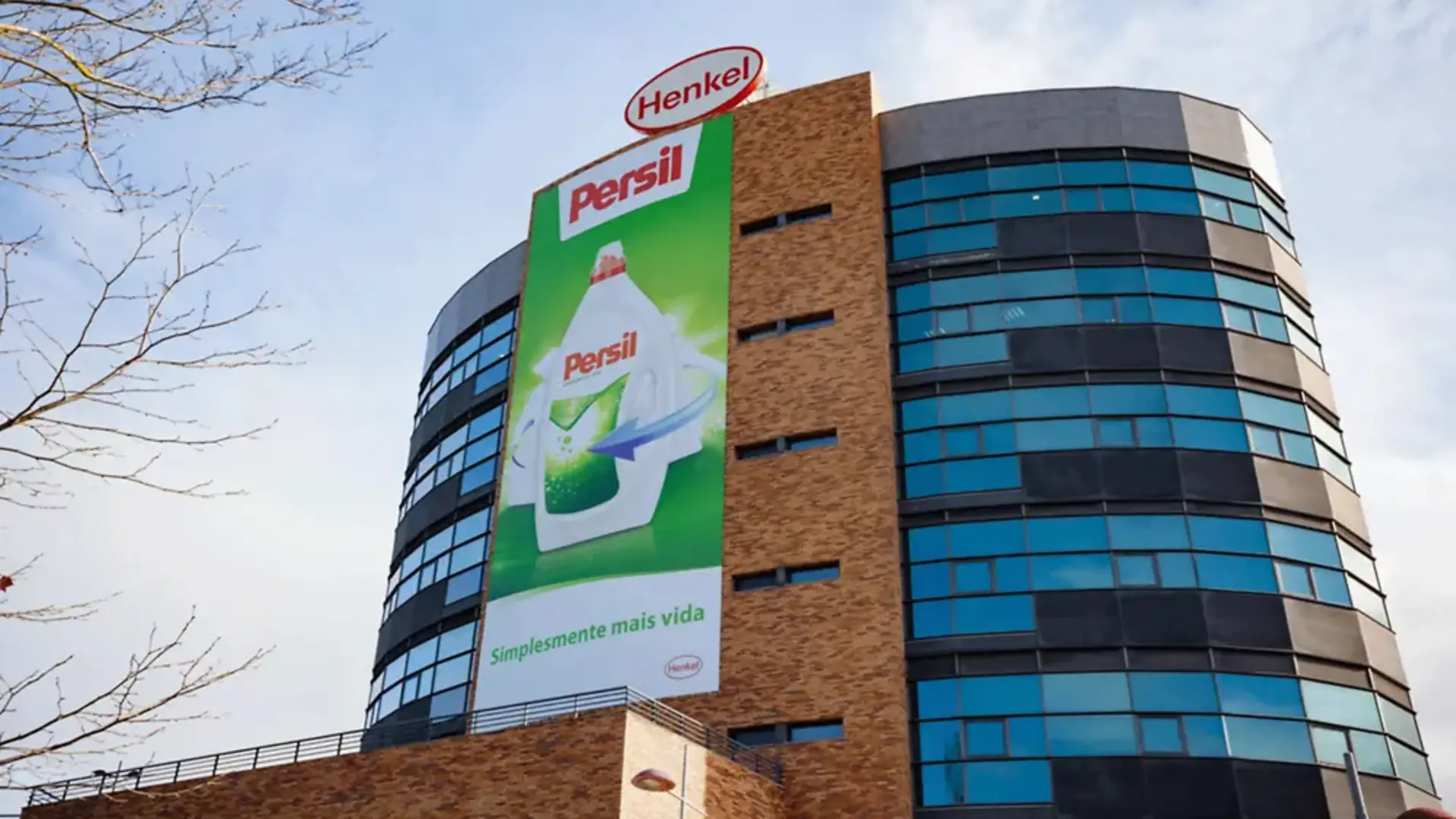 Edifício moderno com logótipo Henkel e grande faixa publicitária da marca Persil, representando a nova sede da Henkel Portugal inaugurada em 2007 no Parque de Negócios de Sacavém.
