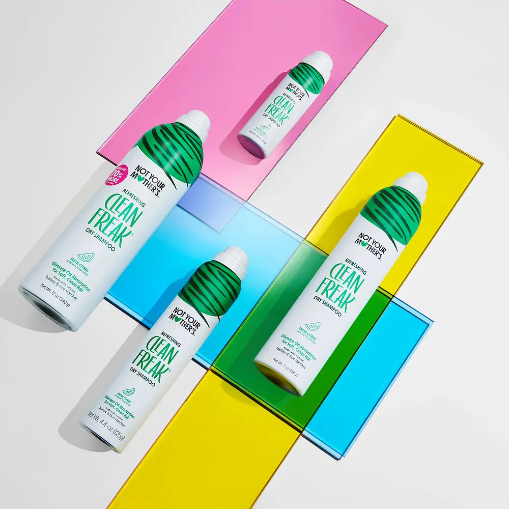 Coleção Clean Freak da Not Your Mother’s com champô seco em vários formatos, apresentada sobre um fundo colorido.