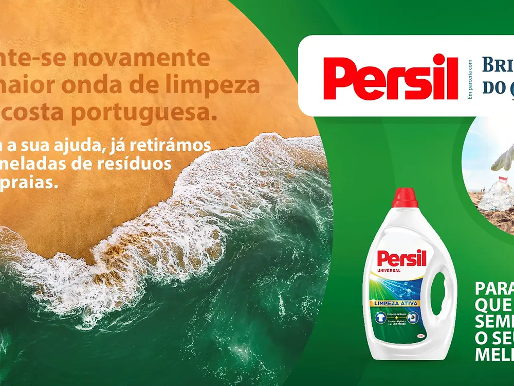 Imagem de uma onda vista de cima a rebentar na costa, acompanhada de embalagens de produtos Persil sobre um fundo verde, com o slogan “Junte-se novamente à maior onda de limpeza da costa portuguesa”.