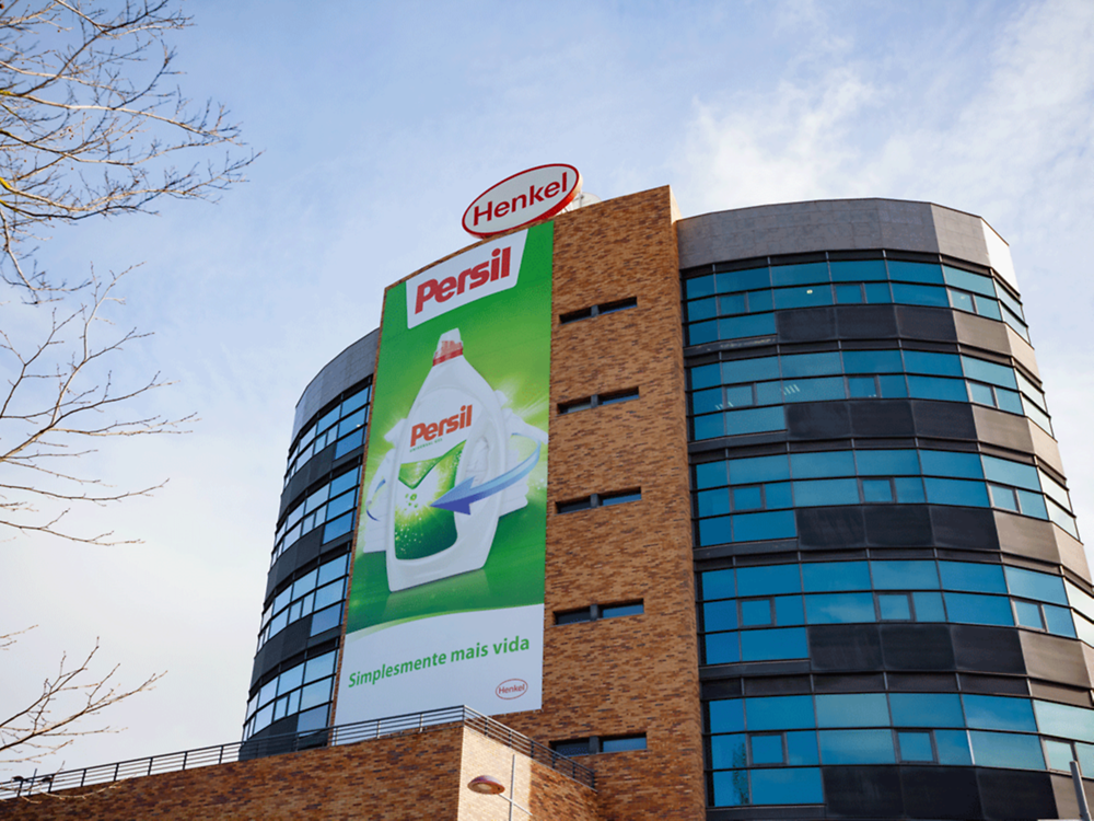 Edifício semicircular da empresa com o logotipo oval da Henkel no telhado e um grande anúncio do Persil na fachada.