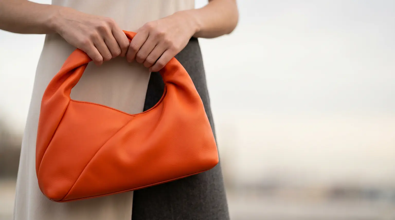 Mala em couro laranja segurada por uma pessoa, exemplo da aplicação das soluções de revestimentos especiais da Stahl para os setores da moda e do luxo.
